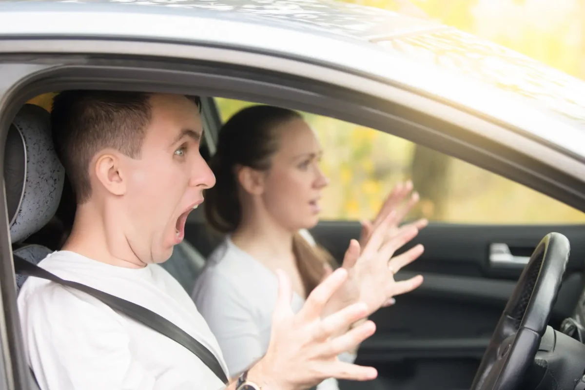 Two people reacting anxiously inside a car.