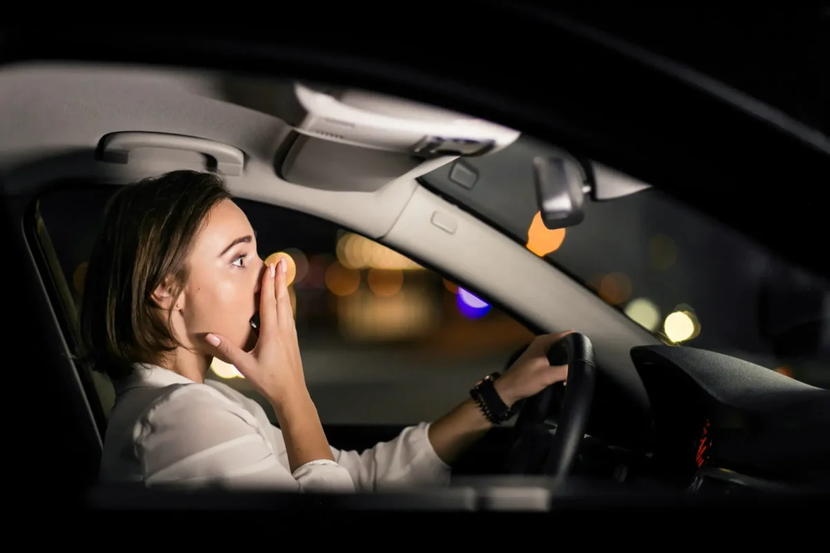 Anxious woman driving at night, illustrating fear of highway driving.